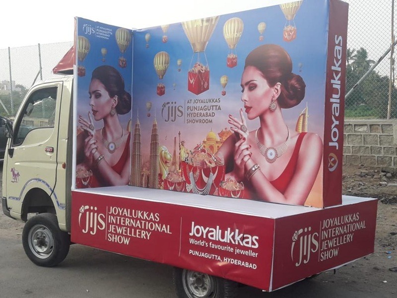 Tata Ace vehicle fully wrapped with a vibrant brand advertisement, driving through a high-traffic commercial area.